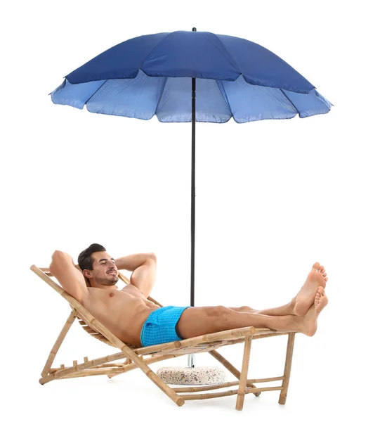 Beyaz arka plana karşı şemsiye altında şezlonsun üzerinde genç adam. Plaj aksesuarları — Stok fotoğraf