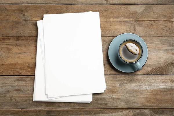 Leere Papierbögen für Broschüren und Kaffeebecher auf Holzgrund, flach gelegt. Attrappe — Stockfoto