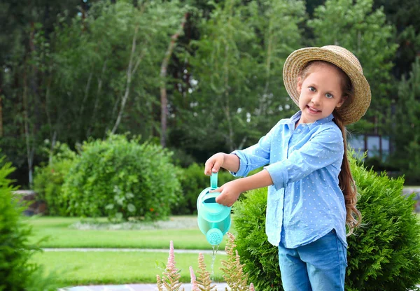 Mała dziewczynka podlewania kwiatów na podwórku. Ogrodnictwo domowe — Zdjęcie stockowe