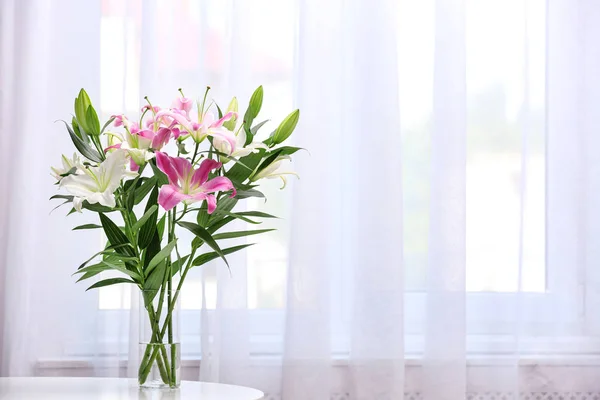 Vase with bouquet of beautiful lilies on white table indoors. Space for text — Stock Photo, Image