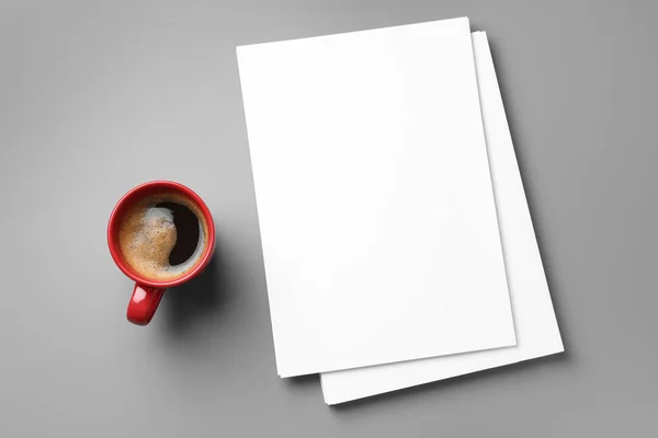 Blanco papieren vellen voor brochure en kopje koffie op grijze achtergrond, platte lay. Mock up — Stockfoto