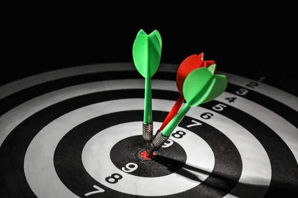 Arrows hitting target on dart board against black background — Stock Photo, Image