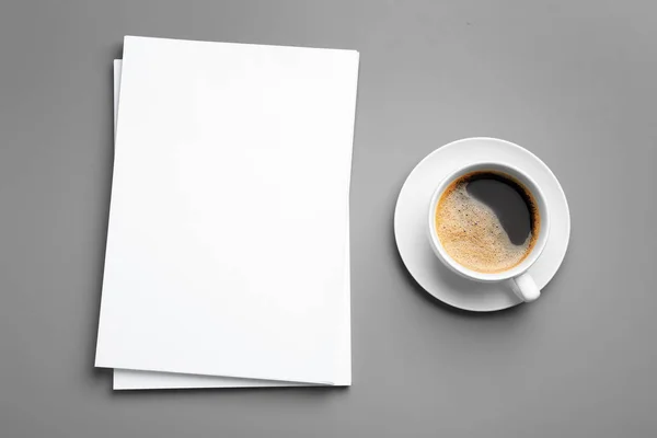 Blanco papieren vellen voor brochure en kopje koffie op grijze achtergrond, platte lay. Mock up — Stockfoto