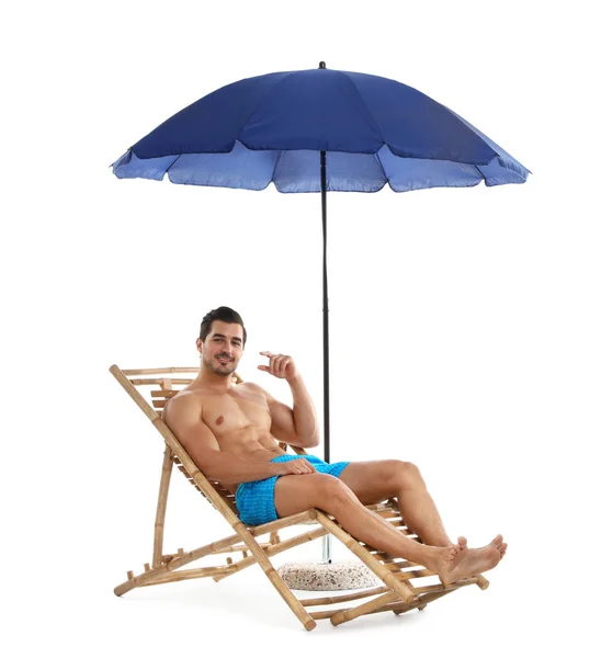 Jonge man op ligstoel onder paraplu tegen witte achtergrond. Strand accessoires — Stockfoto