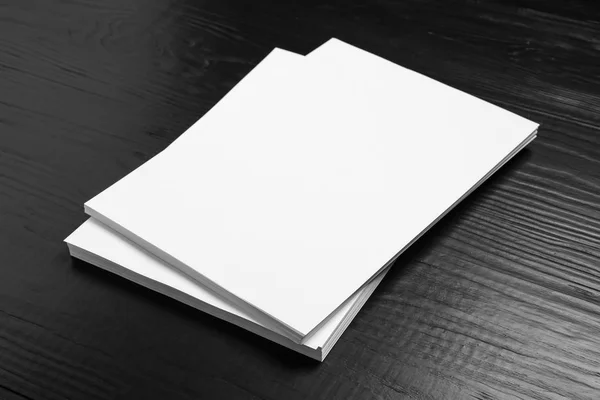 Stapel blanco papieren vellen voor brochure op zwarte houten achtergrond. Mock up — Stockfoto
