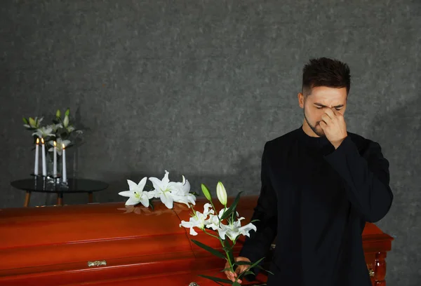 Jovem triste com lírios brancos perto do caixão na funerária — Fotografia de Stock