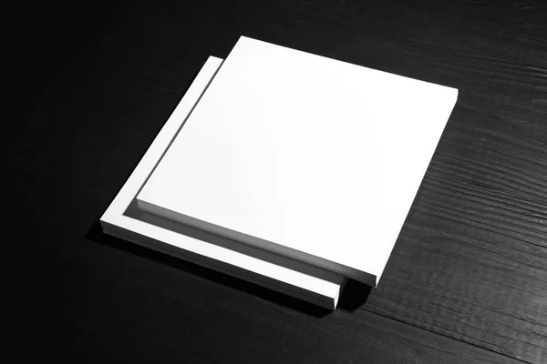 Montón de hojas de papel en blanco para folleto sobre fondo de madera negro. Prepárate. —  Fotos de Stock