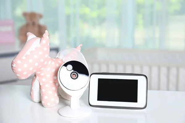 Babyfon mit Kamera und Spielzeug auf dem Tisch im Zimmer. Video-Kindermädchen — Stockfoto
