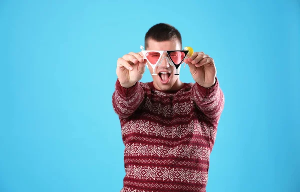 Jeune homme émotionnel en pull de Noël et lunettes de fête sur fond bleu clair — Photo