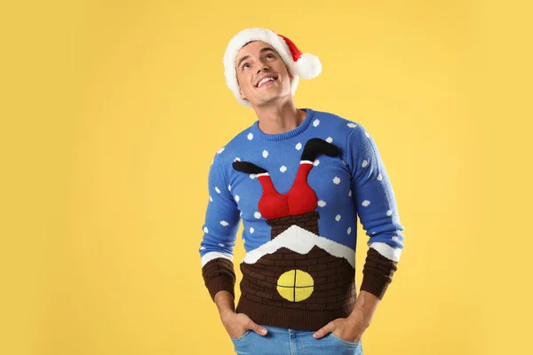 Man in Christmas sweater and Santa hat on yellow background — Stock Photo, Image