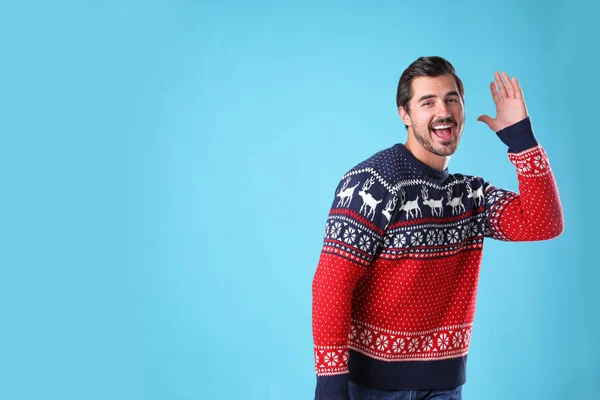 Portrait de jeune homme heureux en pull de Noël sur fond bleu clair. Espace pour le texte — Photo