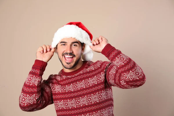 Retrato de hombre joven en jersey de Navidad y sombrero de Santa sobre fondo beige — Foto de Stock