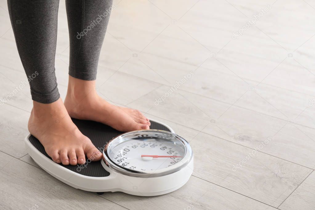 Woman standing on scales indoors, space for text. Overweight problem