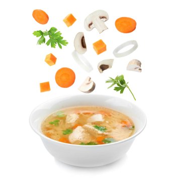 Beyaz arka planda ev yapımı tavuk çorbası kase içine düşen birçok farklı maddeler