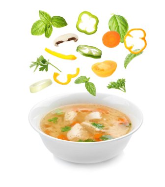 Beyaz arka planda ev yapımı tavuk çorbası kase içine düşen birçok farklı maddeler