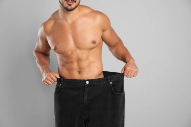 Gri arka plan üzerinde eski büyük boy kot ince vücut ile genç adam, closeup görünümü