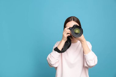 Açık mavi arka planda fotoğraf çeken profesyonel fotoğrafçı. Metin için alan