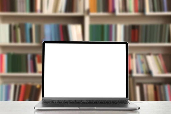 现代笔记本电脑，在图书馆的桌子上有空屏幕。设计空间 — 图库照片