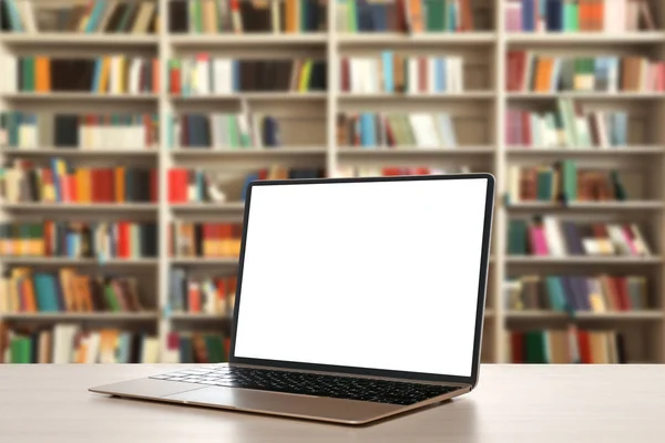 Modern laptop with empty screen on table in library. Space for design — Stock Photo, Image