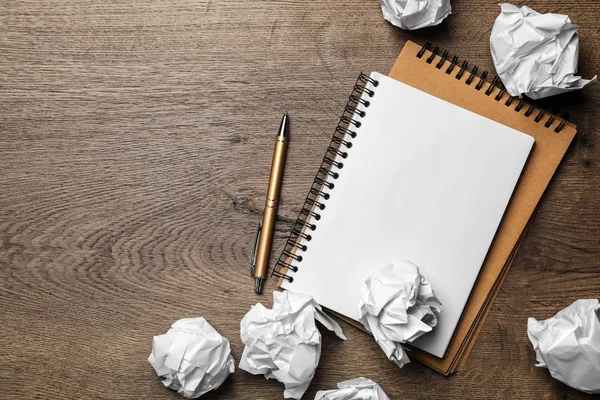 Notebook vazio com caneta e bolas de papel amassadas em mesa de madeira, flat lay. Espaço para texto — Fotografia de Stock