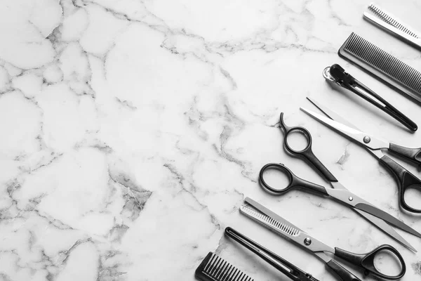 Плоска композиція з ножицями та іншими аксесуарами для перукарів на білому мармуровому тлі. Простір для тексту — стокове фото