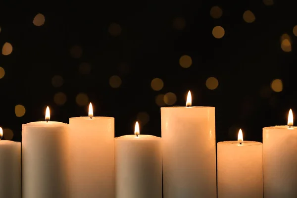 Горящие свечи на черном фоне с размытыми огнями — стоковое фото