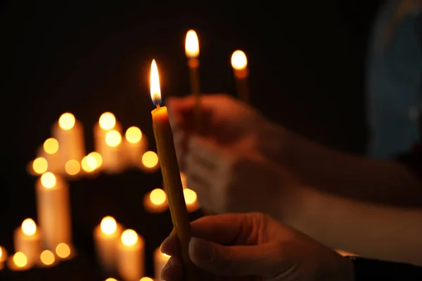 Kobieta trzyma płonącej świecy w ciemności przed niewyraźne tło, zbliżenie — Zdjęcie stockowe