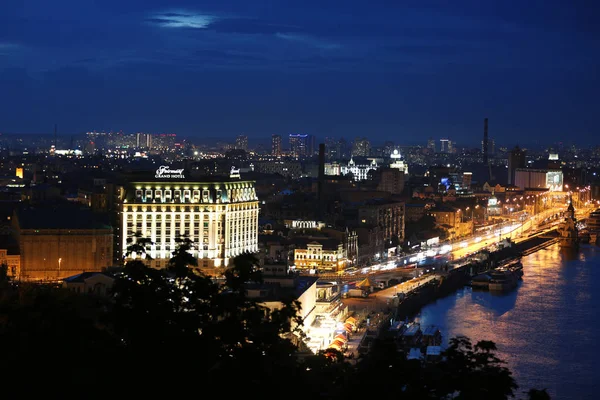Київ, Україна-21 травня 2019: прекрасний вид на нічний міський пейзаж зі освітленою будівлями біля річки та мосту — стокове фото