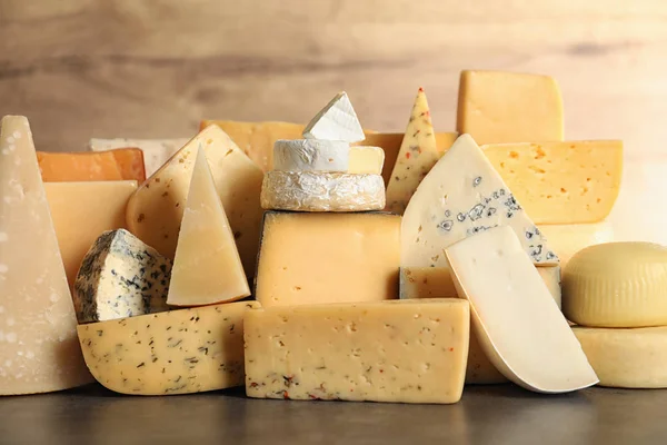 Diferentes tipos de queso delicioso en la mesa sobre fondo de madera — Foto de Stock