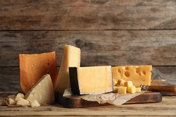 Diferentes tipos de delicioso queijo na mesa contra fundo de madeira — Fotografia de Stock