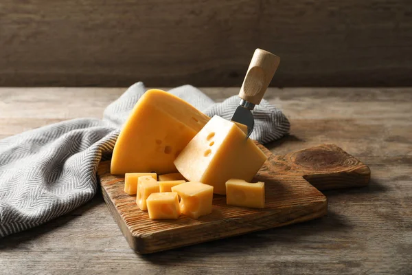 Σανίδα σερβιρίσματος με νόστιμο τυρί σε ξύλινο τραπέζι — Φωτογραφία Αρχείου