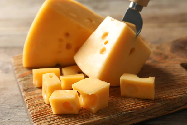Servírovatelné prkno s lahodnými sýry na dřevěném stole, zaostřená — Stock fotografie