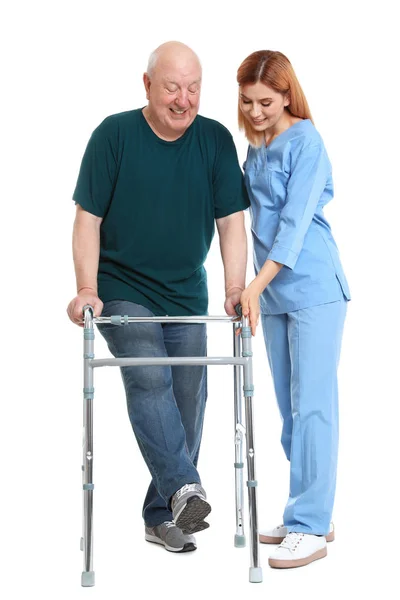 Επιστάτης βοηθώντας τον ηλικιωμένο άνθρωπο με το βάδισμα πλαίσιο σε λευκό φόντο — Φωτογραφία Αρχείου
