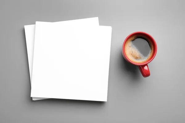 Blanco papieren vellen voor brochure en kopje koffie op grijze achtergrond, platte lay. Mock up — Stockfoto