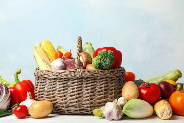 Frisches Gemüse und Weidenkorb auf weißem Holztisch — Stockfoto