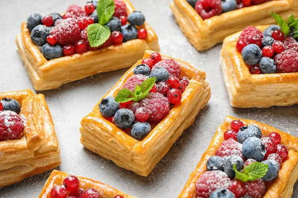 Fresh delicious puff pastry with sweet berries on grey table — Stock Photo, Image