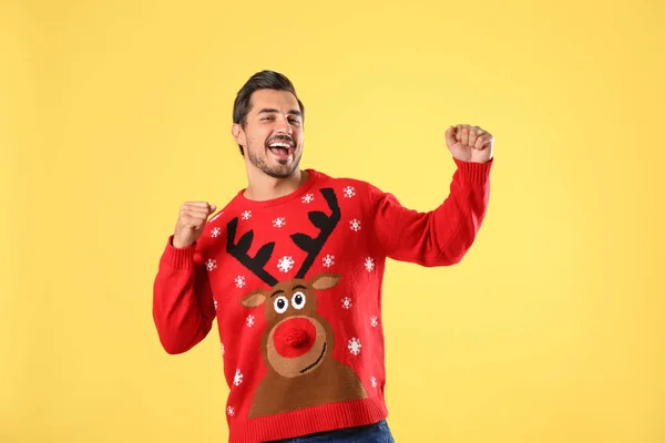 Portrait of happy young man in Christmas sweater on yellow background — Stock Photo, Image