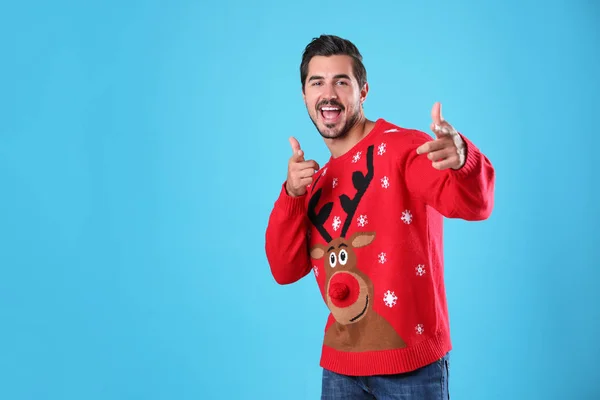 Portrait of happy young man in Christmas sweater on light blue background — Stock Photo, Image