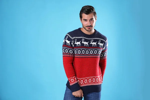 Portrait of happy young man in Christmas sweater on light blue background — Stock Photo, Image