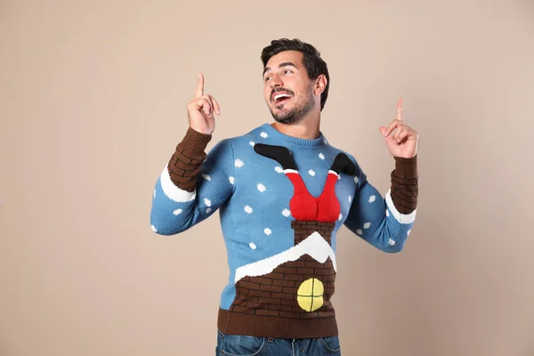 Happy young man in Christmas sweater on beige background — Stock Photo, Image
