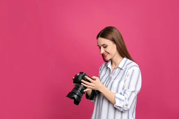 Profesionální fotograf s moderním fotoaparátem na růžovém pozadí — Stock fotografie
