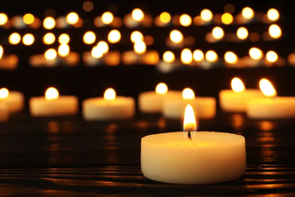 Płonąca świeca na czarnym stole przed niewyraźne tło, miejsce na tekst Zdjęcia Stockowe bez tantiem