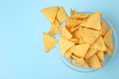 Açık mavi arka planda lezzetli Meksika nachos cips cam kase, üst görünüm