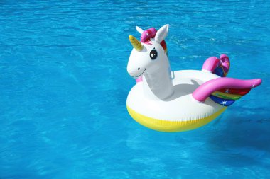 Güneşli bir gün yüzme havuzunda yüzen komik şişme Unicorn yüzük. Metin alanı