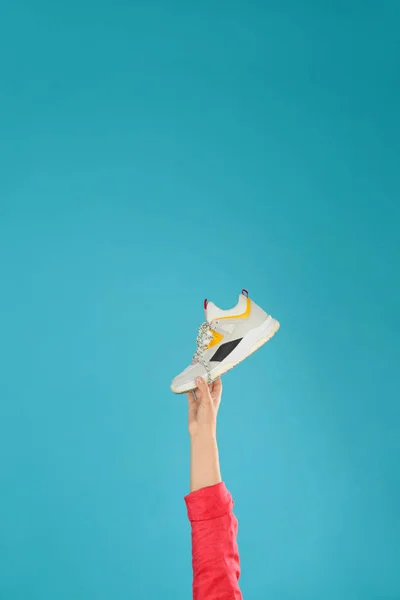 Mujer joven sosteniendo zapato cómodo sobre fondo azul claro, primer plano. Espacio para texto — Foto de Stock