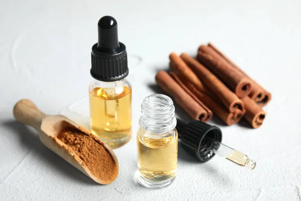 Flessen etherische oliën, kaneelstokjes en poeder op witte tafel — Stockfoto