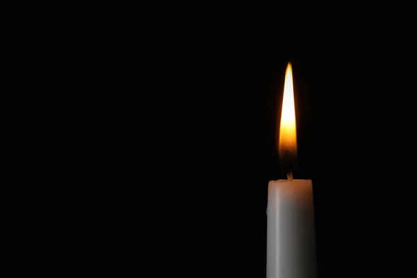 Зажигание свечи на тёмном фоне, место для текста. Символ скорби — стоковое фото