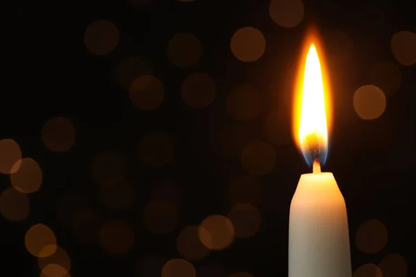 Burning candle on black background with blurred lights, space for text — Stock Photo, Image