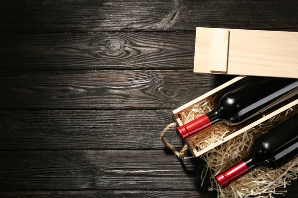 Jaula y botellas de vino sobre mesa de madera, puesta plana. Espacio para texto — Foto de Stock