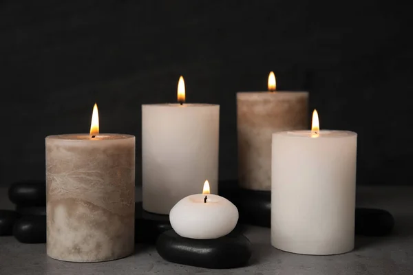 Queimando velas e pedras de spa na mesa cinza — Fotografia de Stock